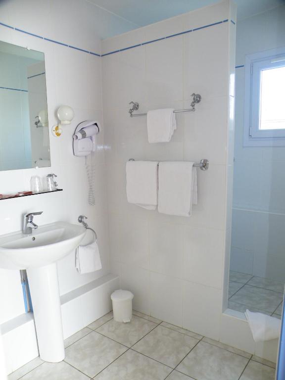 a white bathroom with a sink and a shower at Hôtel de L&#39;Avenue in Saintes
