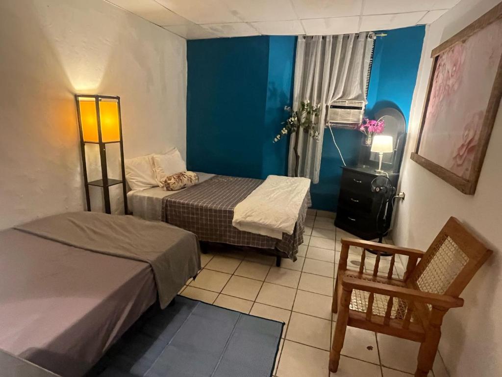 Una pequeña habitación con dos camas y una silla. en casa de elena, en Santa Ana