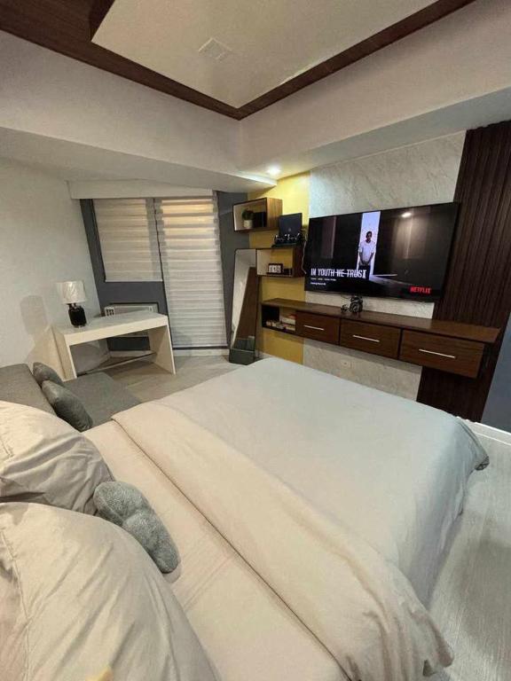 a bedroom with a large bed and a flat screen tv at 22nd-Floor Spacious Studio with Sunrise & Pool Views, Hi-Speed WiFi & Working Space, Netflix, Disney, Kitchen, Wide Balcony in San Fernando