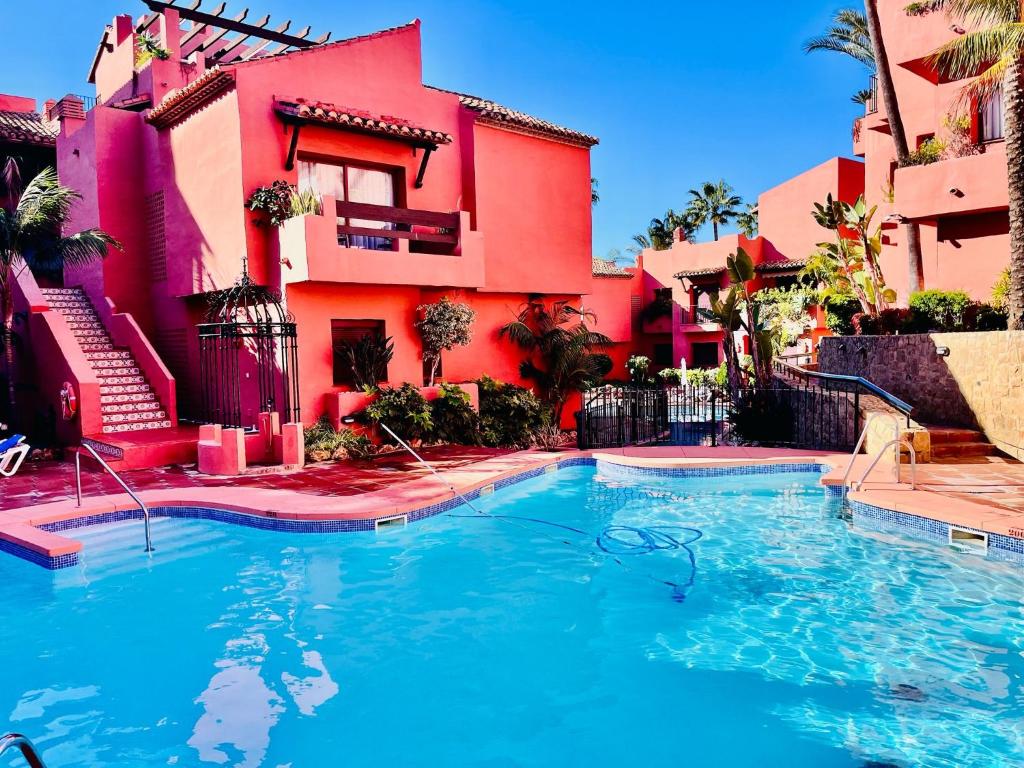 a swimming pool in front of a red building at Estrelicia IV in Marbella