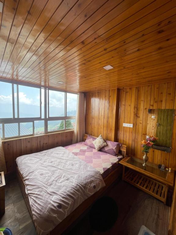 een slaapkamer met een bed in een kamer met houten wanden bij Aamo Homestay in Darjeeling