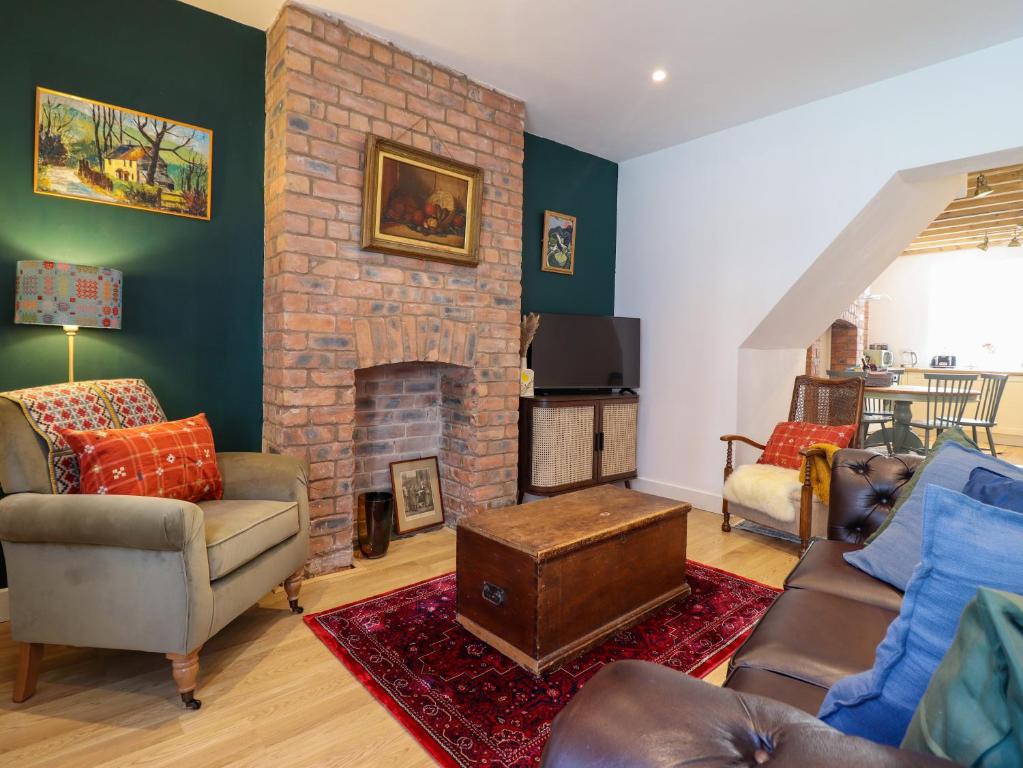 a living room with a brick fireplace and furniture at Derwen House in Llangollen