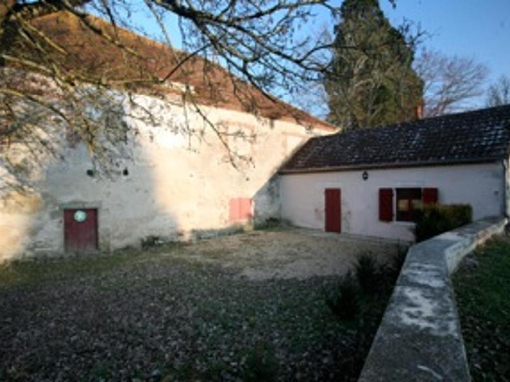 - un bâtiment blanc avec des portes rouges à côté d'une cour dans l'établissement Charmant gîte au château rénové, parc privé, 2 chambres, proche Nevers et circuit Magny Court - FR-1-489-163, à Le Veurdre