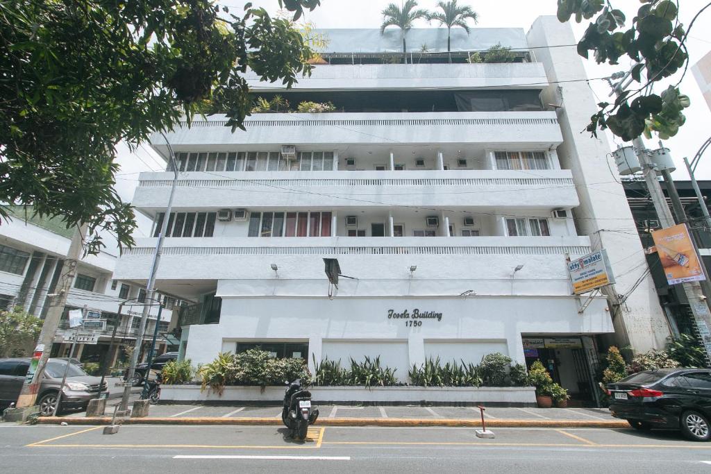 a motorcycle parked in front of a white building at Stay Malate Hostel by RedDoorz in Manila