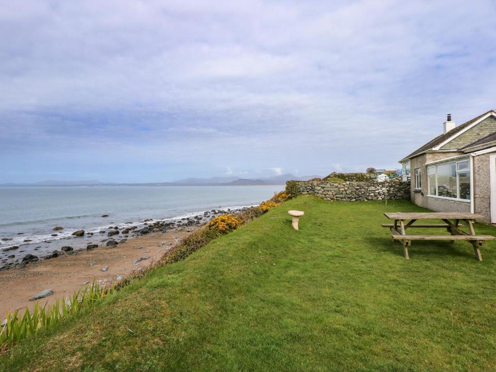 a house with a picnic table next to the ocean at Tegawelon in Harlech