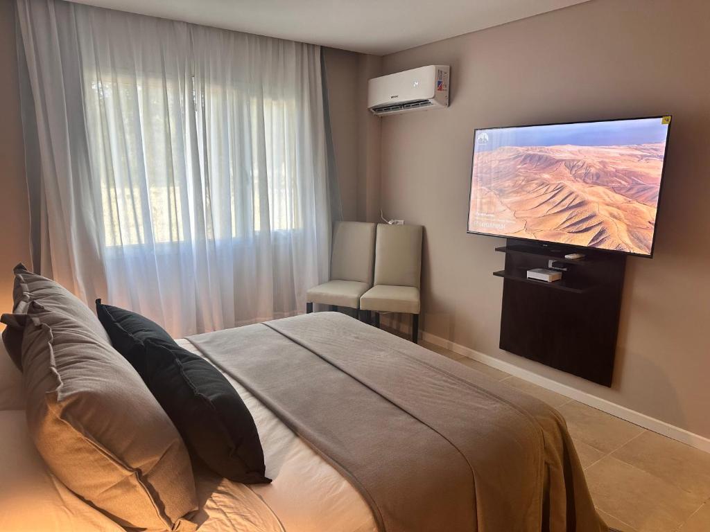 a bedroom with a bed and a flat screen tv at Suite del sol 6 in Pinamar