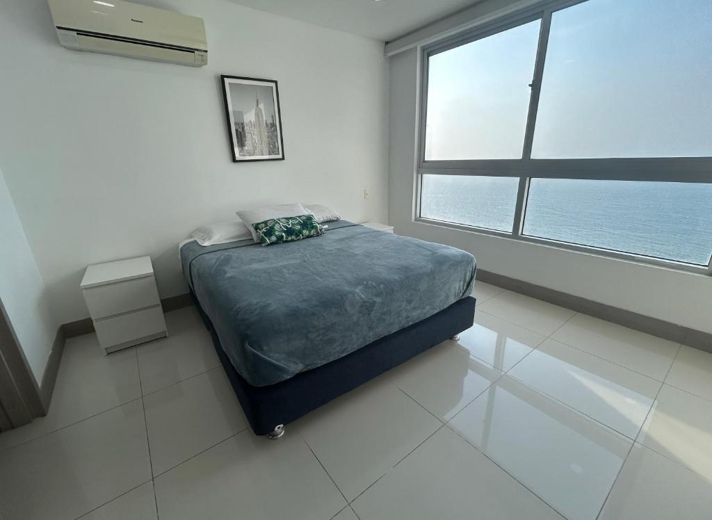 a bedroom with a bed and a large window at Apartamento en Edificio Palmetto Beach frente a la Playa in Cartagena de Indias