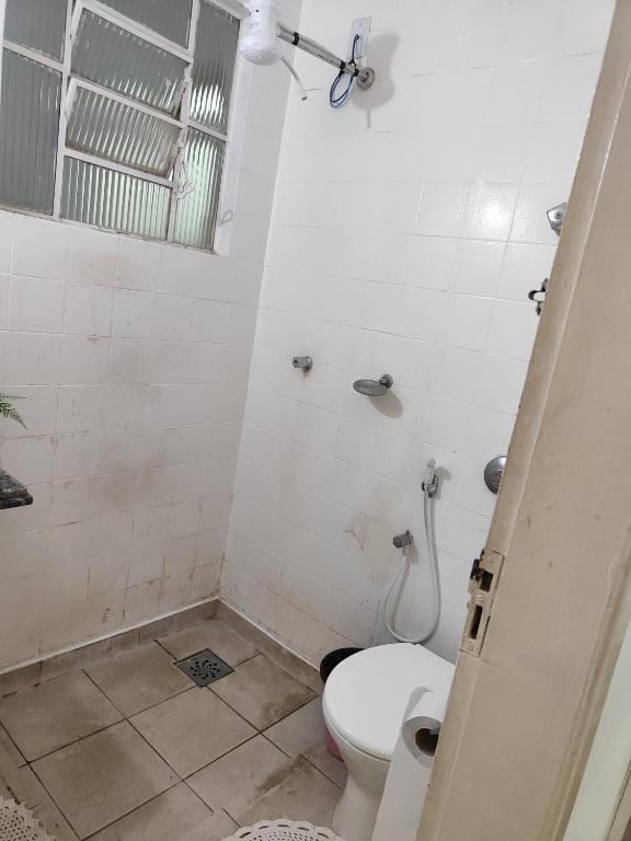 a white bathroom with a toilet and a shower at Pousada Aleha Quarto Casal Rosé in Montes Claros