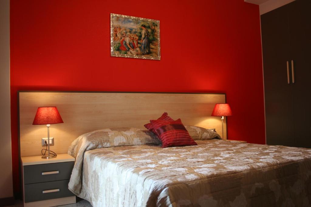 ミラッツォにあるGallery B&b Milazzoの赤い壁のベッドルーム1室、ベッド1台(ランプ2つ付)