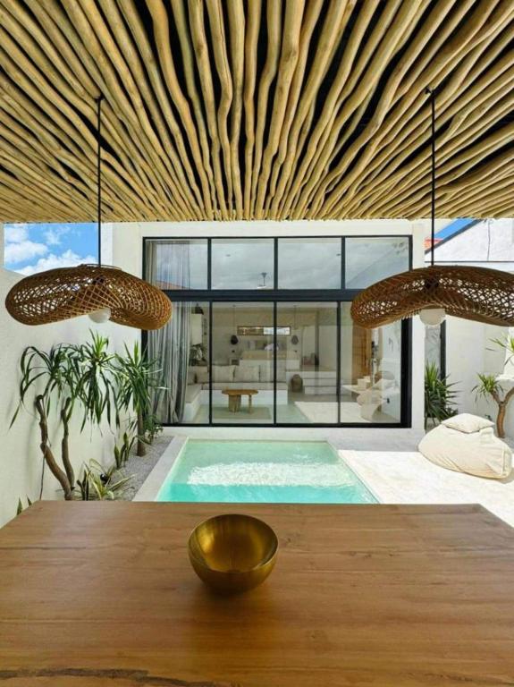 a house with a swimming pool and a wooden table at Ecstatic Villa, heart of Uluwatu in Uluwatu