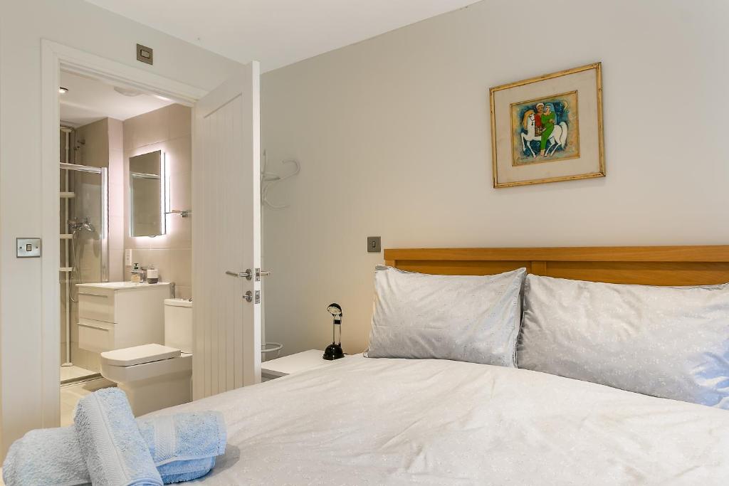 ein Schlafzimmer mit einem weißen Bett und ein Badezimmer in der Unterkunft Cosy 3 Bedroom Home Next to Bicester Village! in Bicester