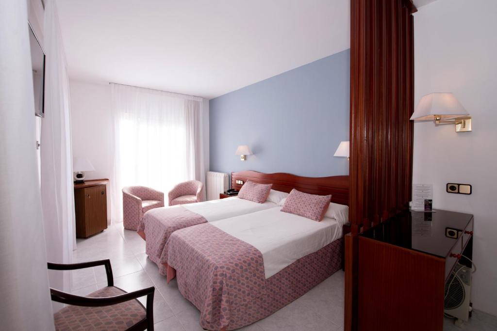 サン・フェリウ・デ・ギホルスにあるHotel Plaçaのベッド、テーブル、椅子が備わるホテルルームです。