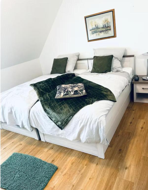 a white bed with a green blanket on it at Baierrefreies Apartment Stielzchen Steinbeck in Recke