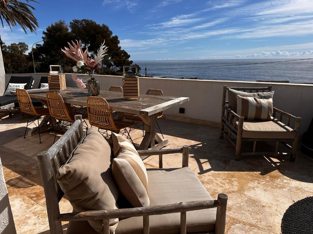 un patio avec une table et des chaises et l'océan dans l'établissement Loft 83380 LES ISSAMBRES, aux Issambres