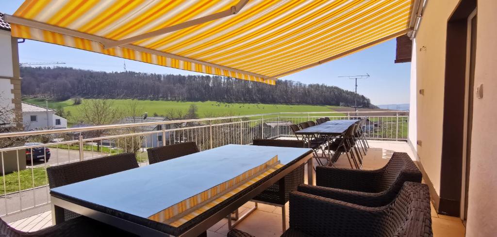 a balcony with tables and chairs and a view of a field at Südschwarzwald Ferienhaus für Gruppen & Monteure in Waldshut-Tiengen