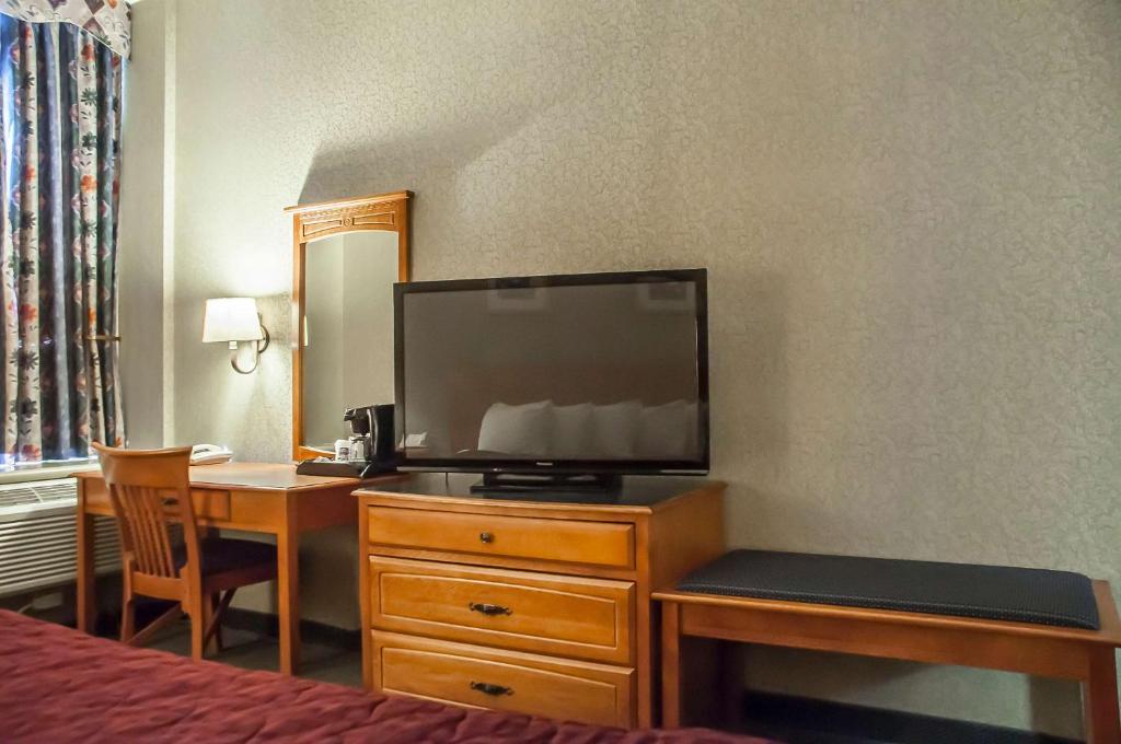 a hotel room with a desk with a television and a bed at Comfort Inn Lundy's Lane in Niagara Falls
