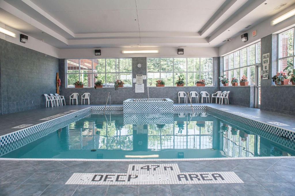 a swimming pool with chairs and a table in a building at Comfort Inn Lundy's Lane in Niagara Falls