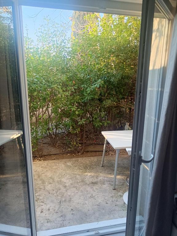 une porte coulissante en verre ouverte avec une table à l'extérieur dans l'établissement Côté green, à Juvignac