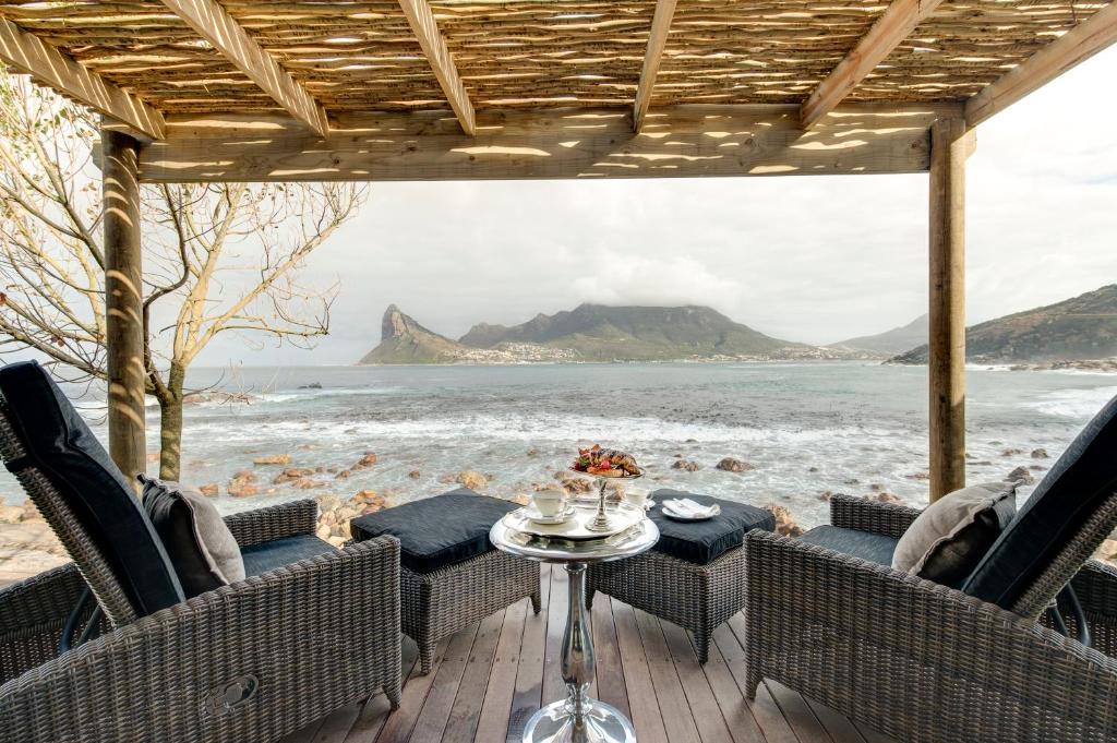 a patio with chairs and a table with a view of the ocean at Tintswalo Atlantic in Hout Bay