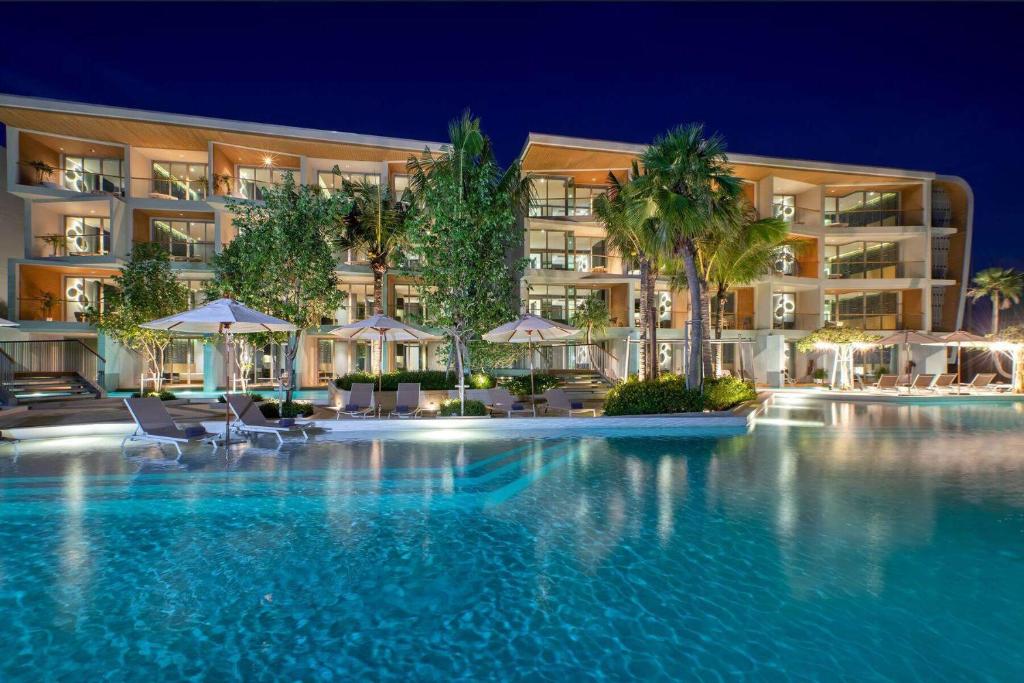 a swimming pool in front of a hotel at night at Wyndham Grand Nai Harn Beach Phuket in Nai Harn Beach