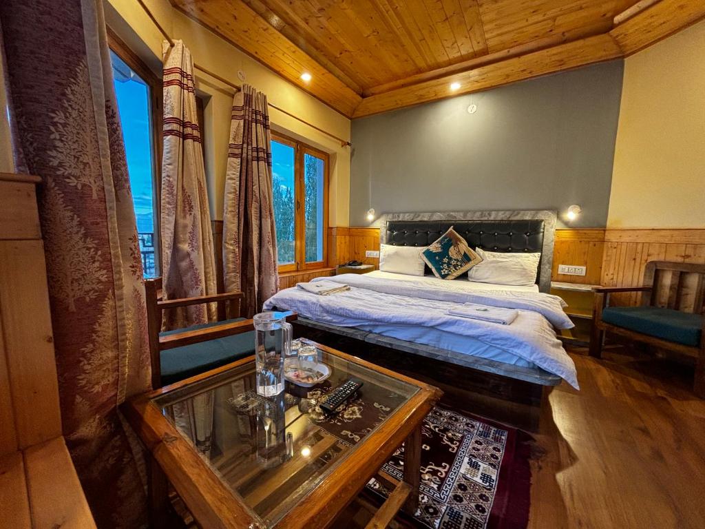a bedroom with a bed and a table and window at Zaltak Guest House and Hostel in Leh