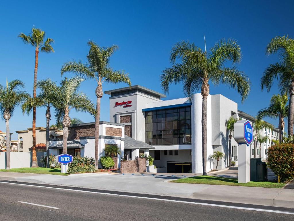 a building with palm trees in front of a street at Hampton Inn by Hilton Costa Mesa Newport Beach in Costa Mesa