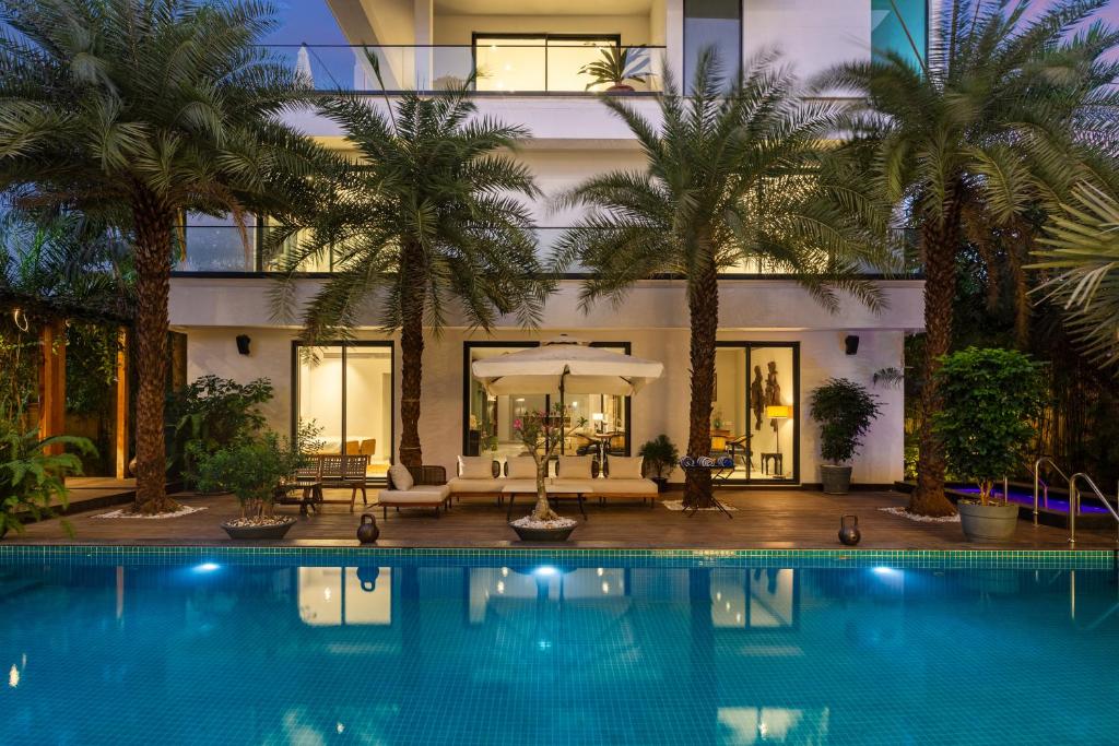 a house with a swimming pool and palm trees at Amorzito by Solitaire Stays in Dona Paula