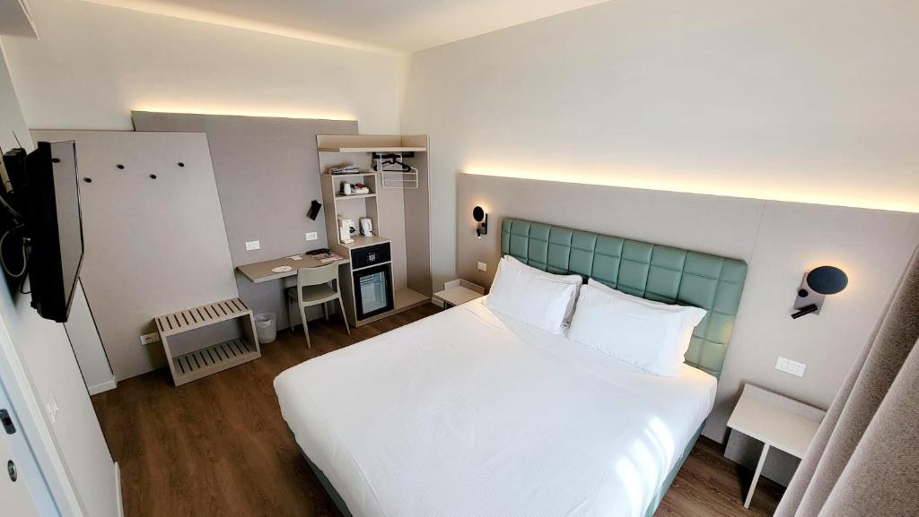 a bedroom with a large white bed and a desk at Hotel Aurora Duino in Duino