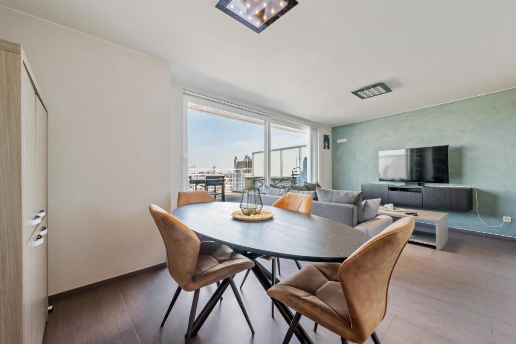ein Wohnzimmer mit Tisch und Stühlen und einer Couch in der Unterkunft Modern Penthouse with Unique Terraces! in Ostende