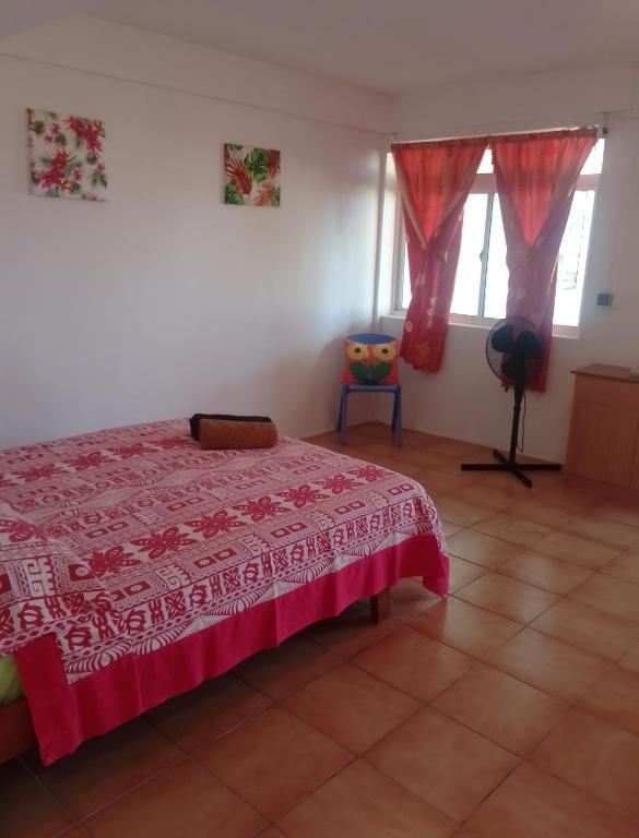 a bedroom with a bed with a red bedspread at Pension Ataha RAIVAVAE in Vaiuru