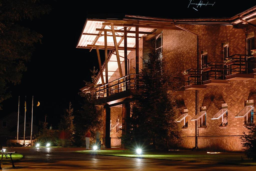 un edificio con un árbol delante de él por la noche en Park-Hotel Butenko Stable en Protsev