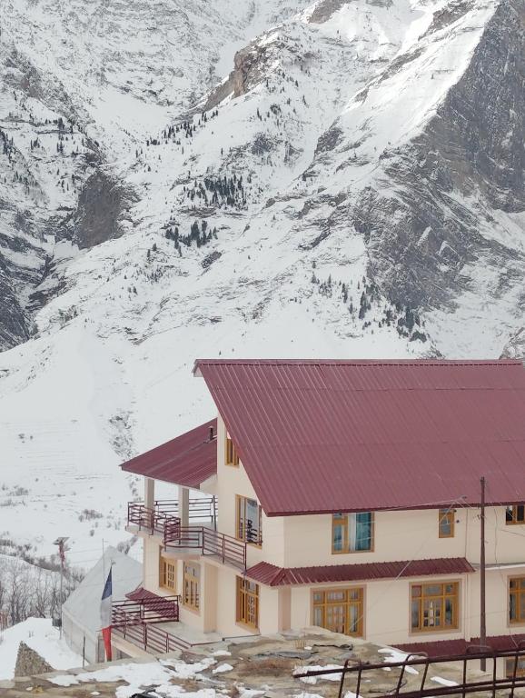 a building with a red roof in front of a snow covered mountain at Gangzing Homestay in Tāndi