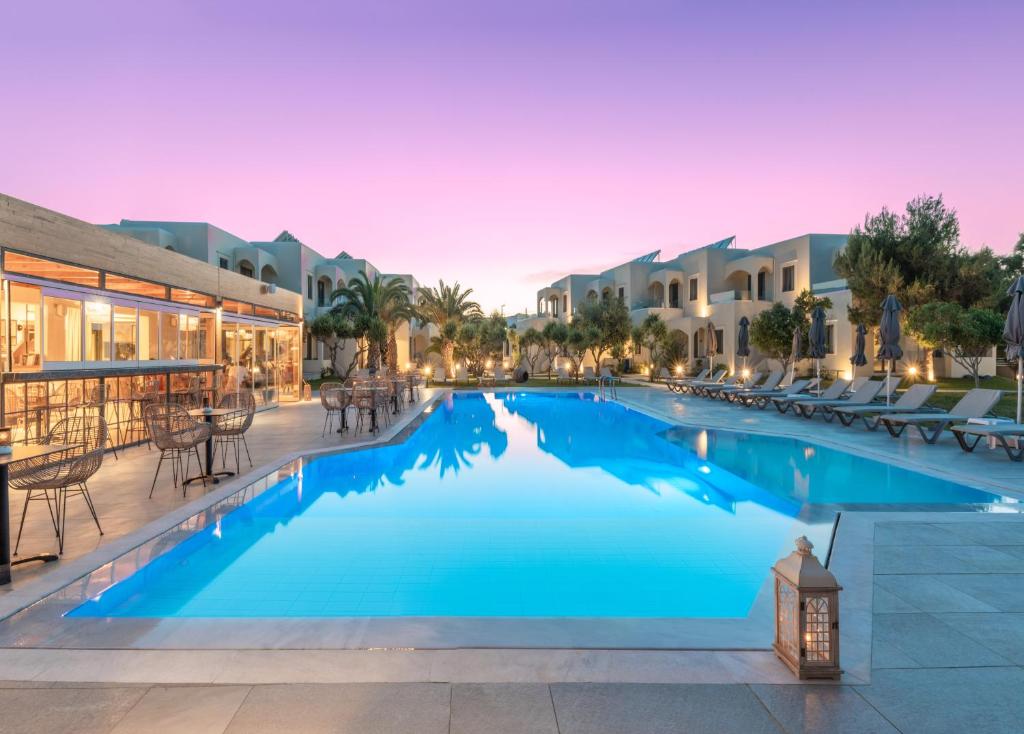a large swimming pool with tables and chairs in a resort at Malena Hotel & Suites - Adults Only by Omilos Hotels in Amoudara Herakliou