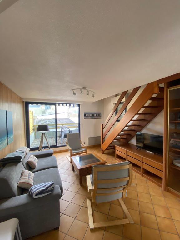 Una sala de estar con un sofá y una escalera. en Duplex 100m de la mer, en Larmor-Plage