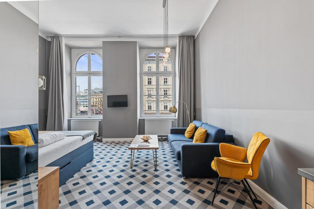 salon z niebieską kanapą i żółtymi krzesłami w obiekcie KH Opera Apartments w Wiedniu
