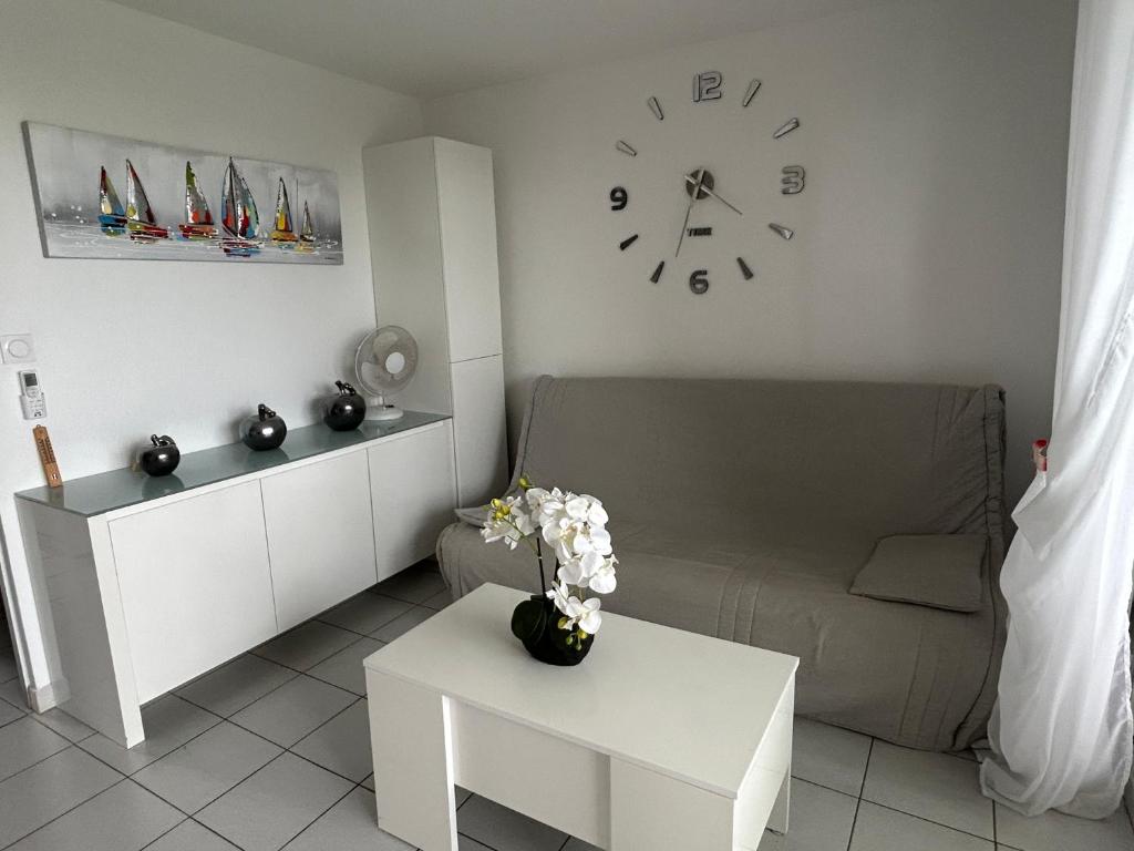 un salon avec un canapé et une horloge au mur dans l'établissement Résidence Azureva - Richelieu, au Cap d'Agde