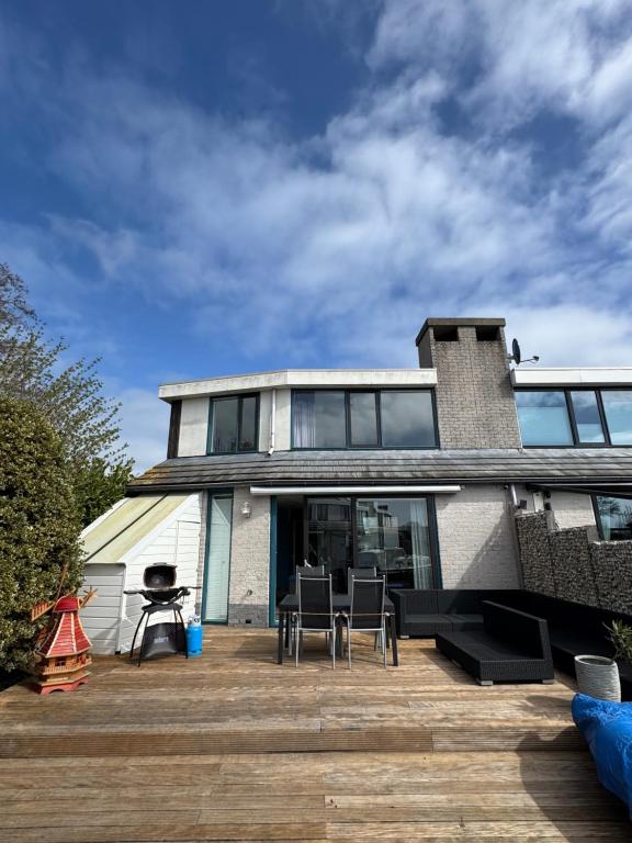 a house with a deck with chairs and tables at Luxe vakantiehuis aan het water, Lemmer in Lemmer