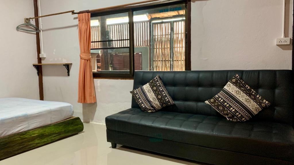 a living room with a green couch and a window at Pakham hostel in Pai