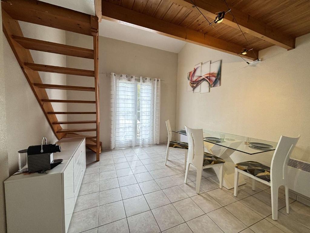 une salle à manger avec une table en verre et des chaises blanches dans l'établissement Maison 2 pièces -mezz CHATELAILLON PLAGE - CL080-029, à Châtelaillon-Plage