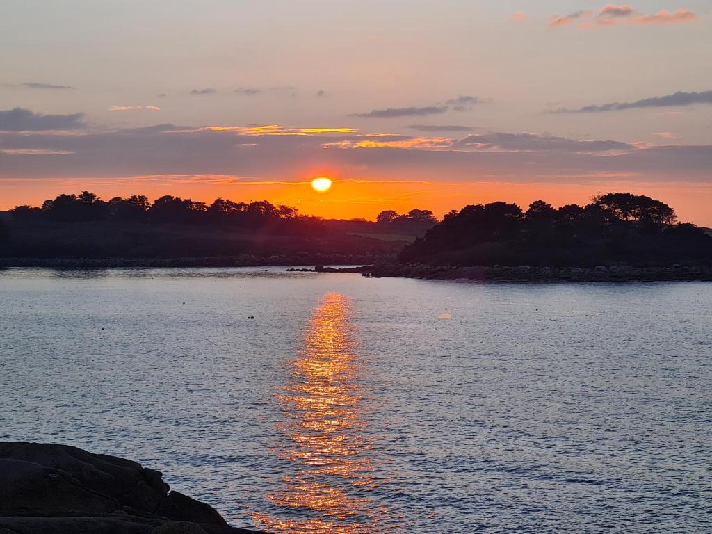 un coucher de soleil sur un plan d'eau avec le soleil couchant dans l'établissement Macareux, à Perros-Guirec