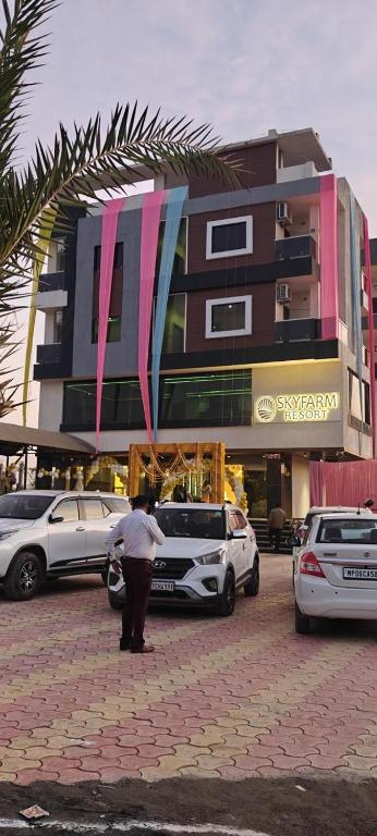 a man standing next to a car parked in front of a building at Skyfarm Resort in Barāgaon