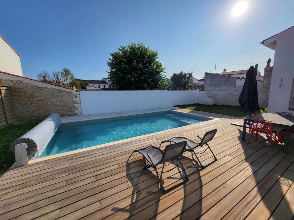 - une piscine avec 2 chaises et une table sur une terrasse en bois dans l'établissement Villa Beau Soleil, à Aytré