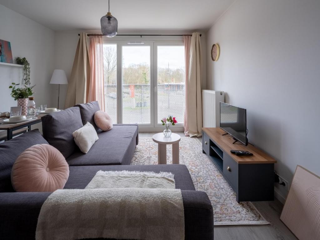a living room with a couch and a tv at Suite Business CDG Villepinte Parking in Tremblay-En-France