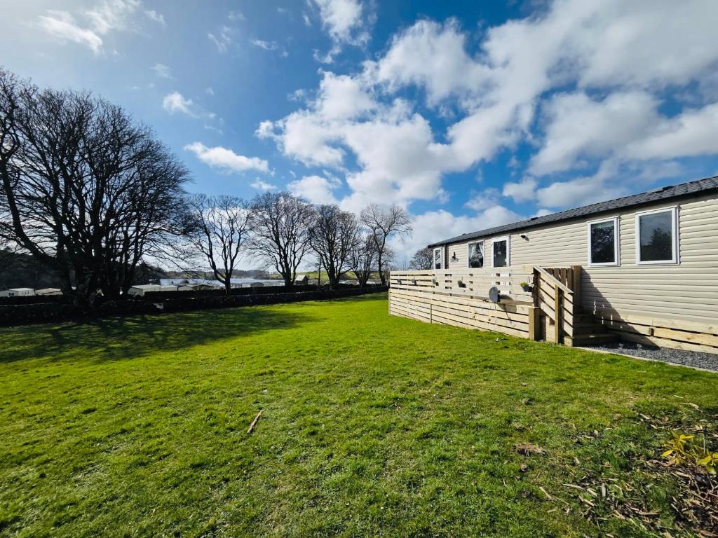 a large grassy yard next to a building at The Canny View at Three Lochs Holiday Park in Balminnoch 3 bedroom sleeps upto 8 guests in Newton Stewart