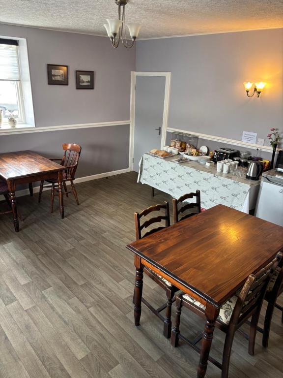 eine Küche und ein Esszimmer mit Holztischen und Stühlen in der Unterkunft Fife Arms Guest House in Keith