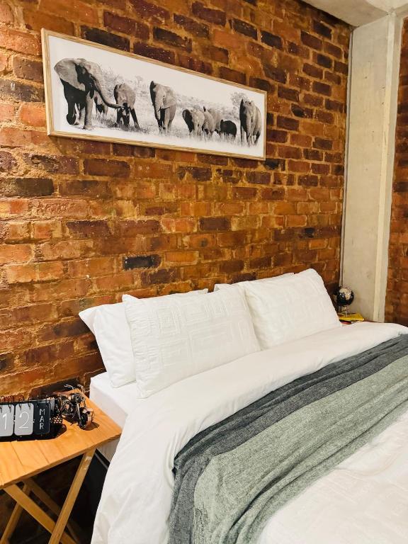 a bed in a room with a brick wall at The Nook at Maboneng -24hr security, WiFi, cozy home in Johannesburg