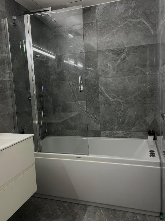 a bathroom with a white tub and a shower at Sea view Mercury Tower, Rooftop infinity Pool in St. Julianʼs