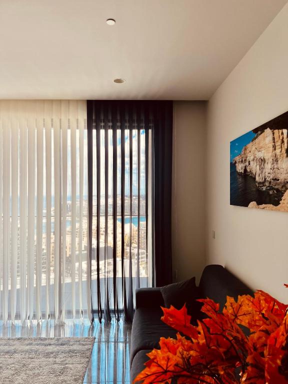 a living room with a couch and a large window at Sea view Mercury Tower, Rooftop infinity Pool in St. Julianʼs