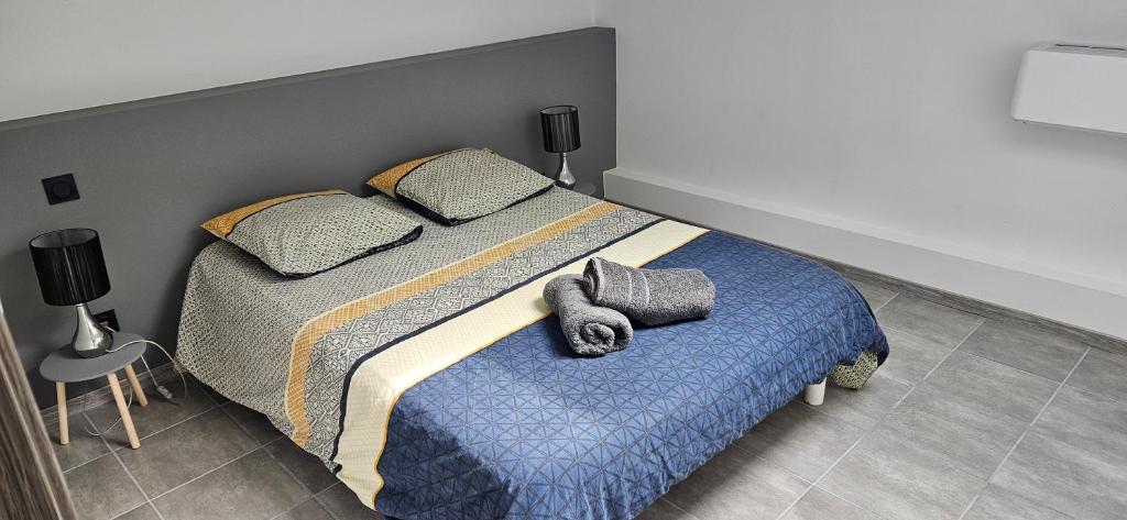 Un dormitorio con una cama con una manta azul y almohadas. en Duplex 2 chambres avec extérieur, en Suze-la-Rousse