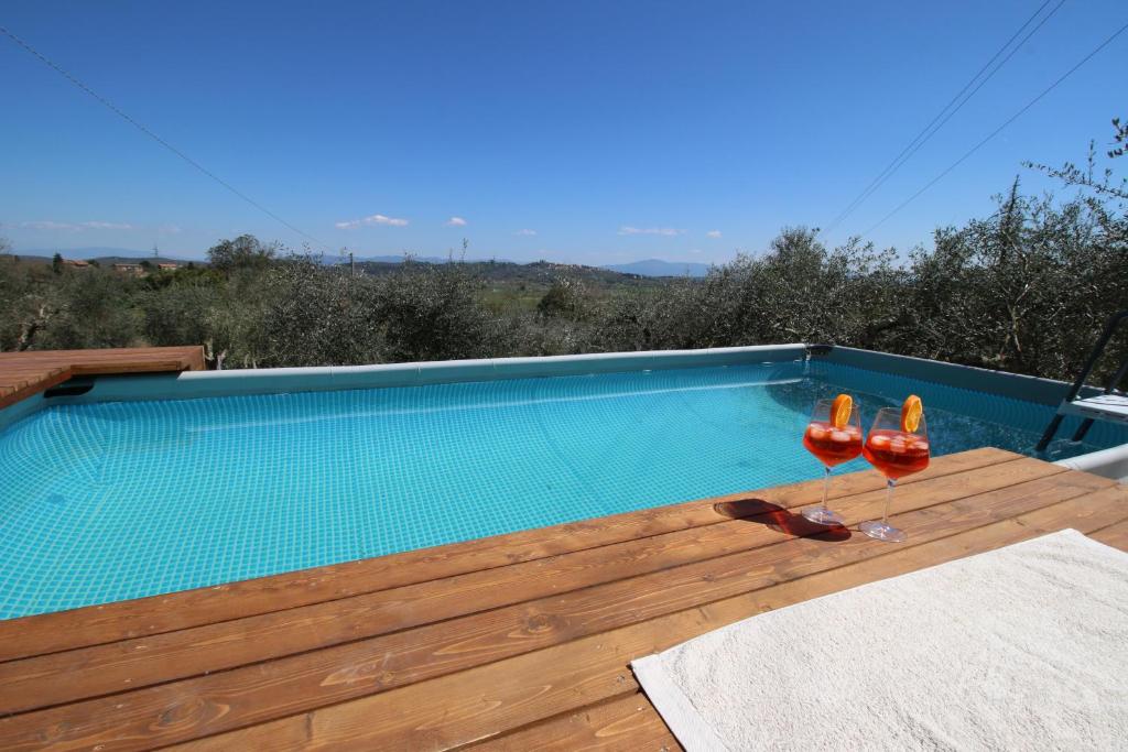 a swimming pool on a deck with two wine glasses at Happy Tuscany in Rigomagno